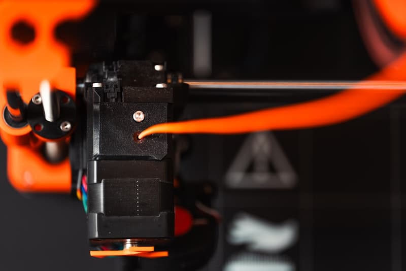 Close-up of 3D printer nozzle with orange filament